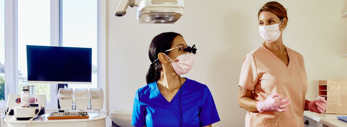 ACDQ Dentiste souriant à une patiente sur la chaise d'examination